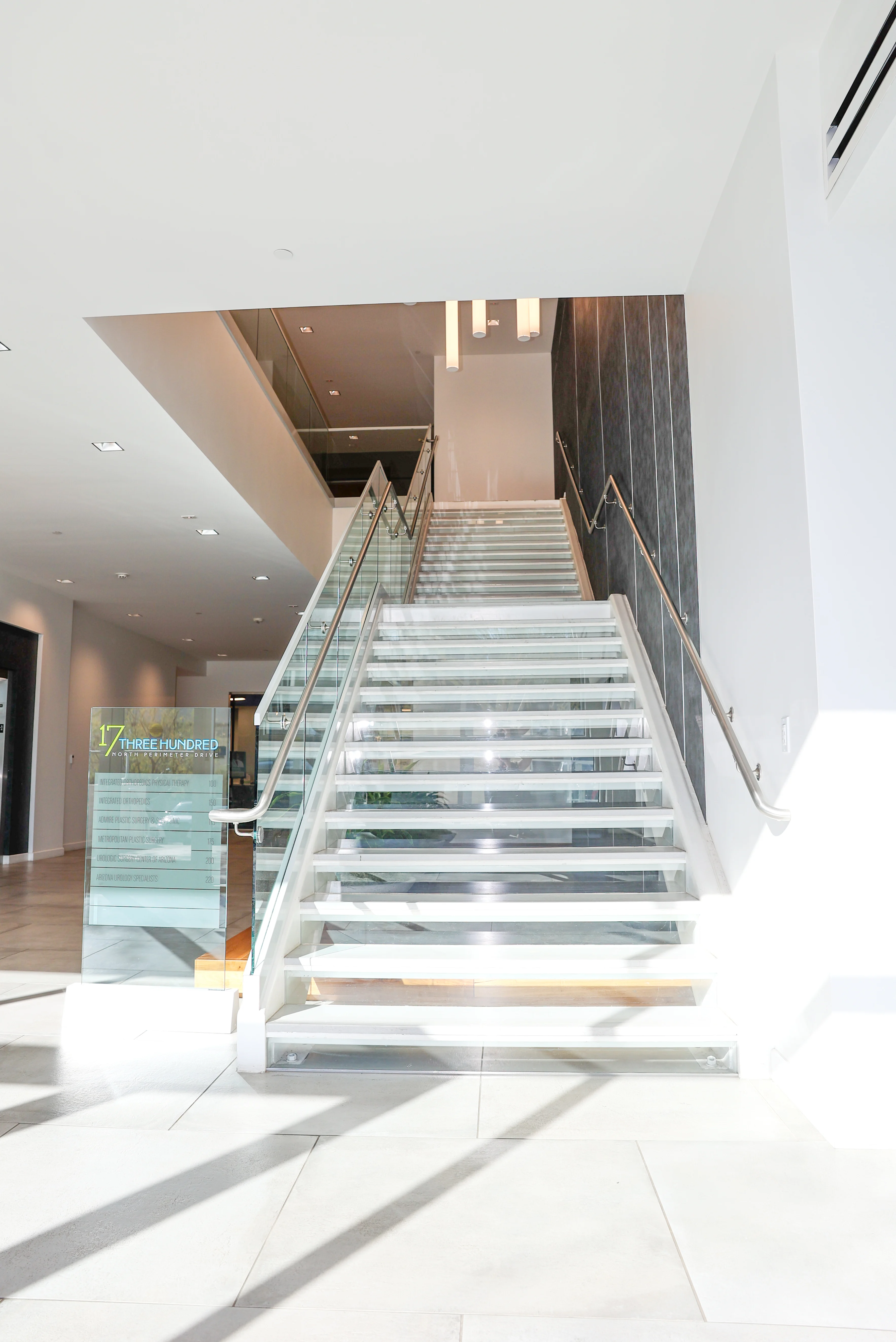 Bright lobby staircase with glass railing at 17300 North Perimeter Drive in Scottsdale where Metropolitan Plastic Surgery is located.