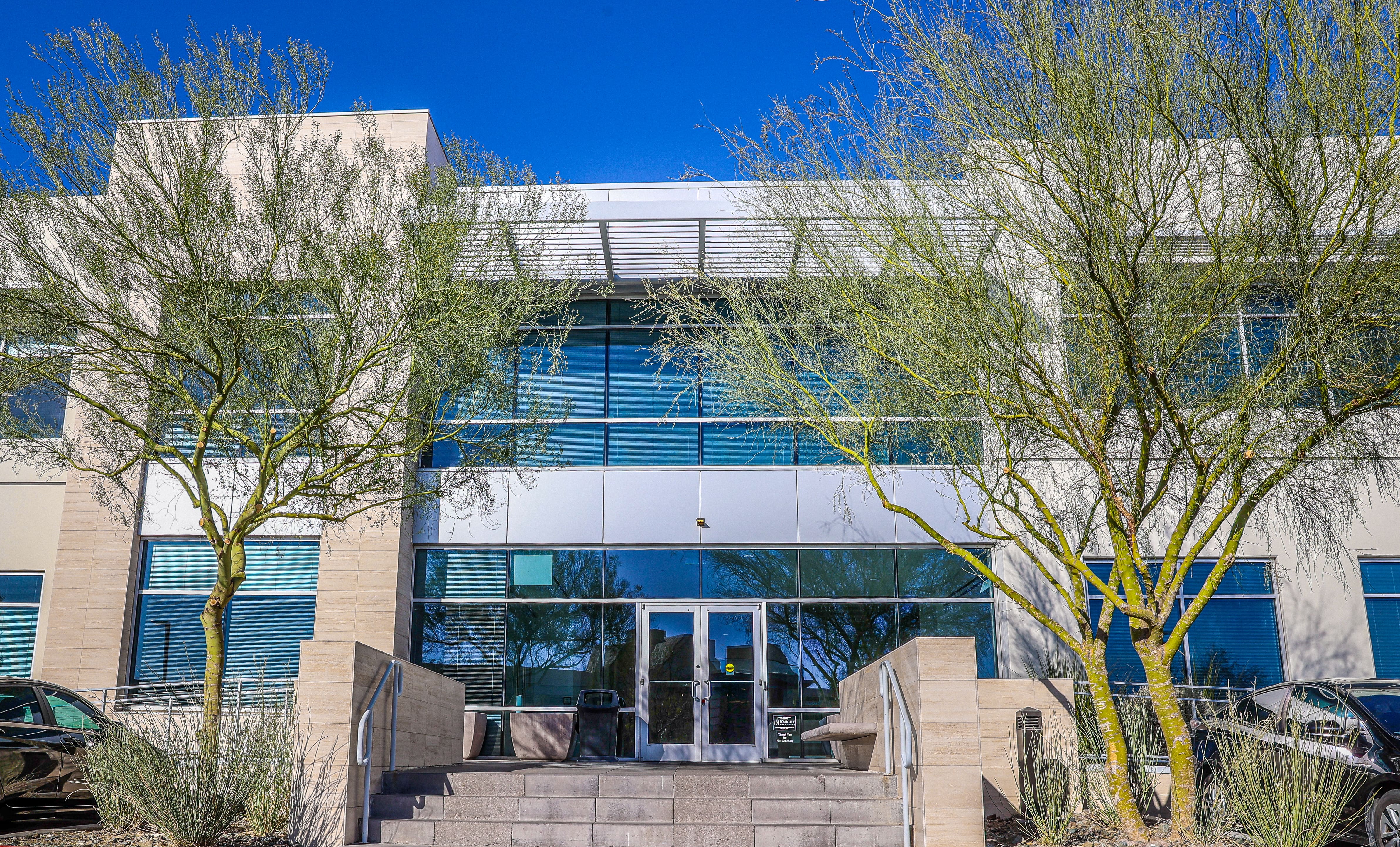 Exterior of professional building housing Metropolitan Plastic Surgery in Scottsdale Arizona with desert landscaping and clear blue sky.
