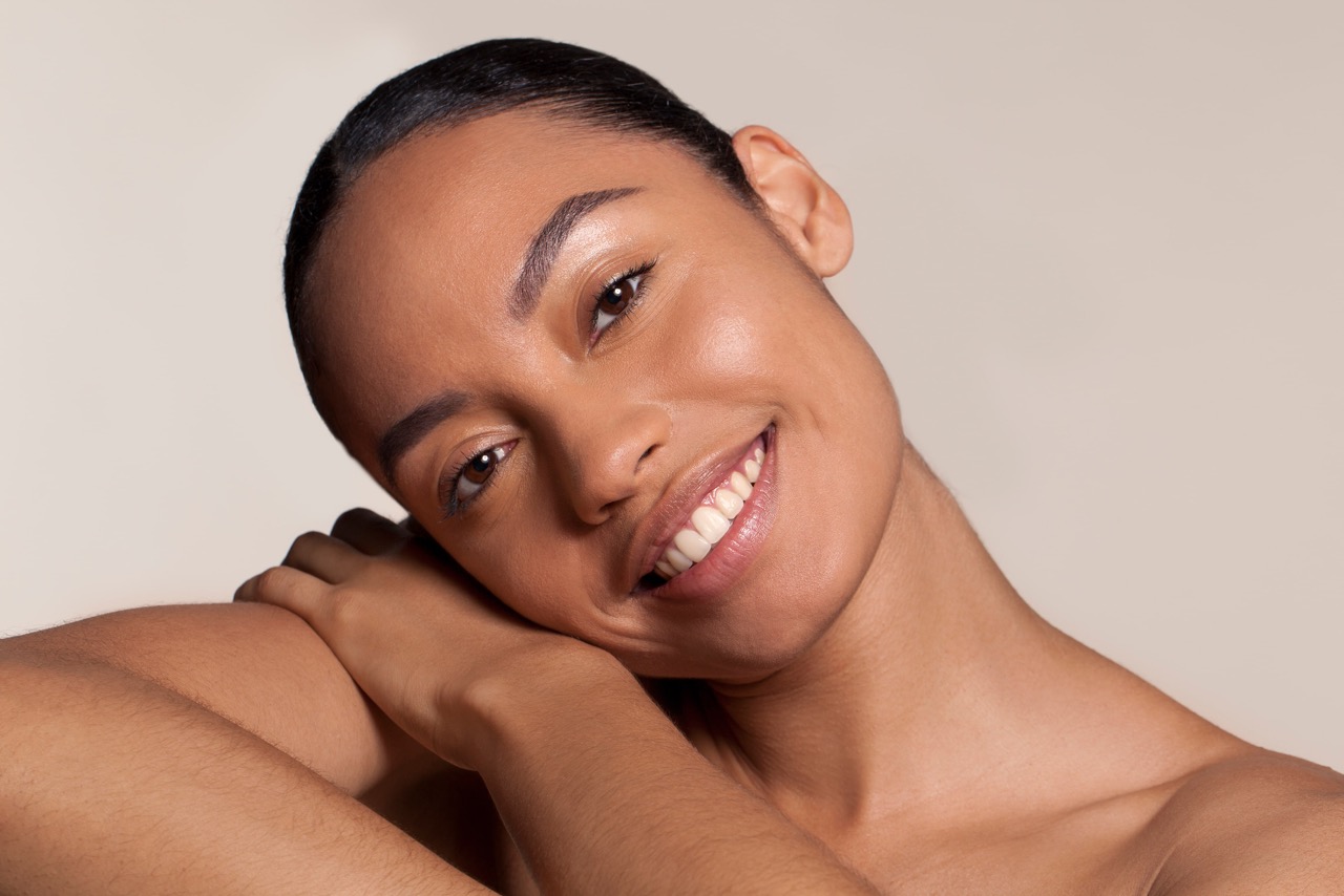 A woman smiling with radiant, smooth skin after facial fat grafting, highlighting youthful facial contours and volume restoration.