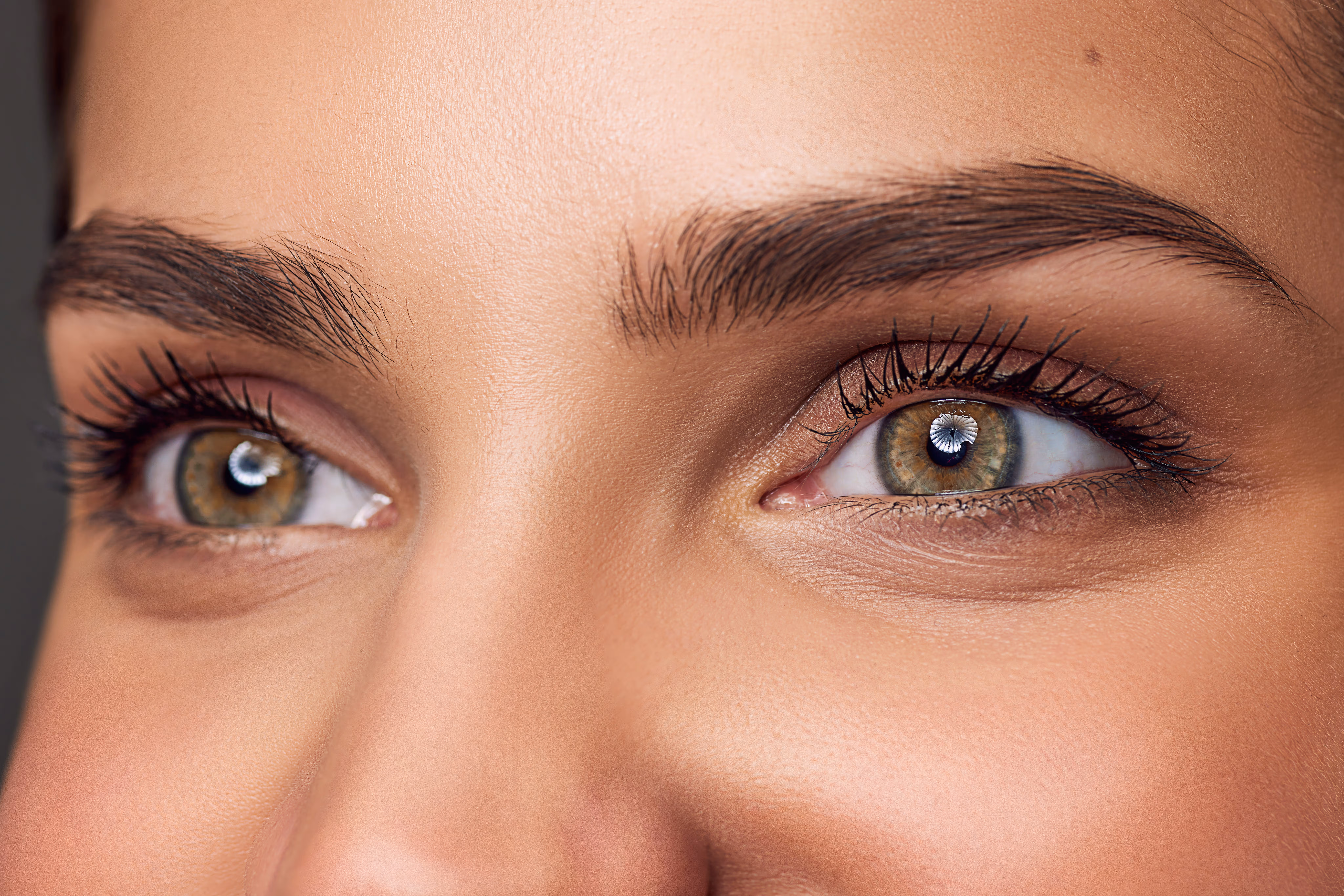 Close-up of bright green eyes with smooth eyelids and defined brows, illustrating rejuvenation from upper blepharoplasty.