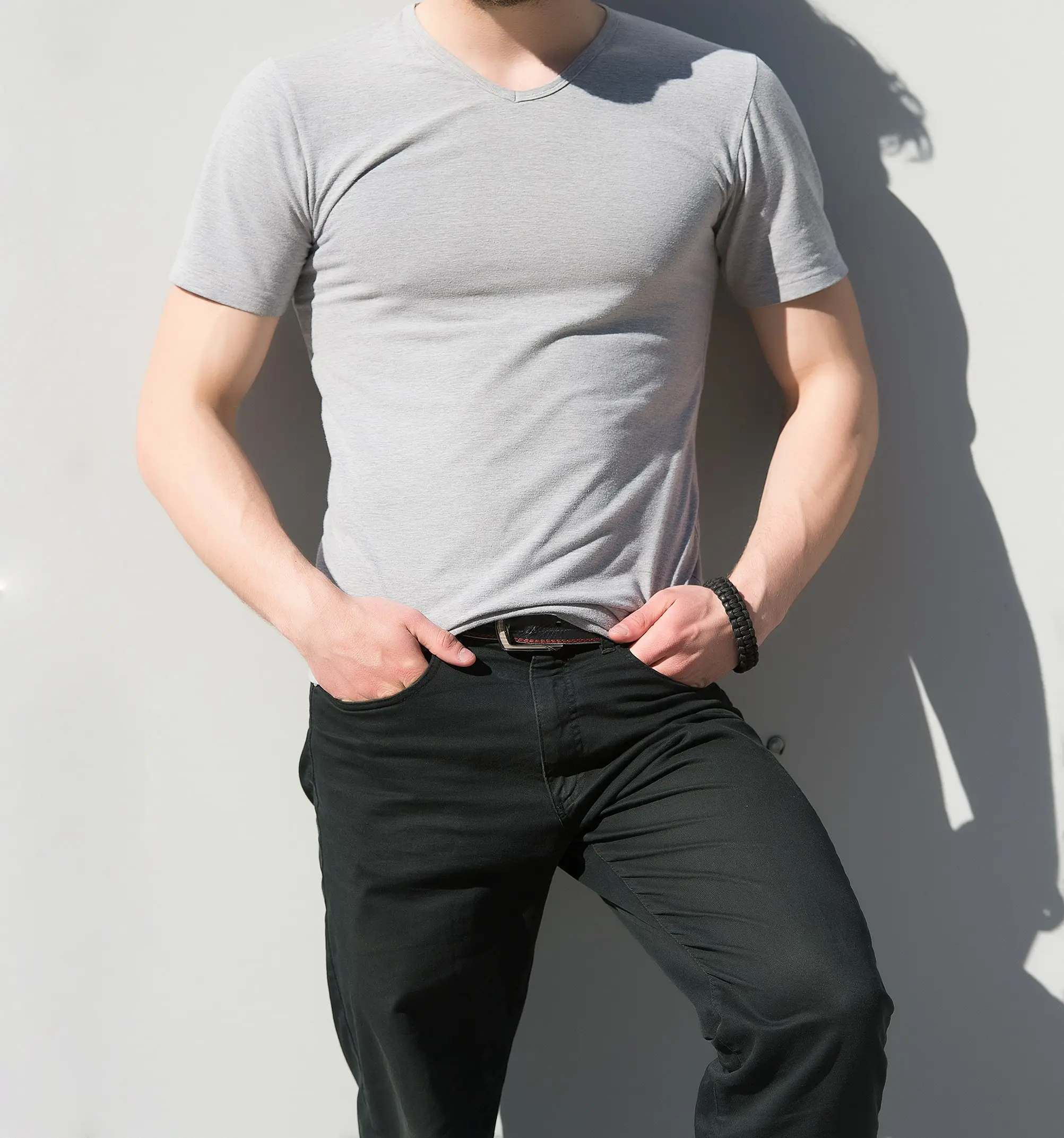 Man wearing a fitted t-shirt confidently standing in natural light, showing a flat chest profile after gynecomastia treatment.