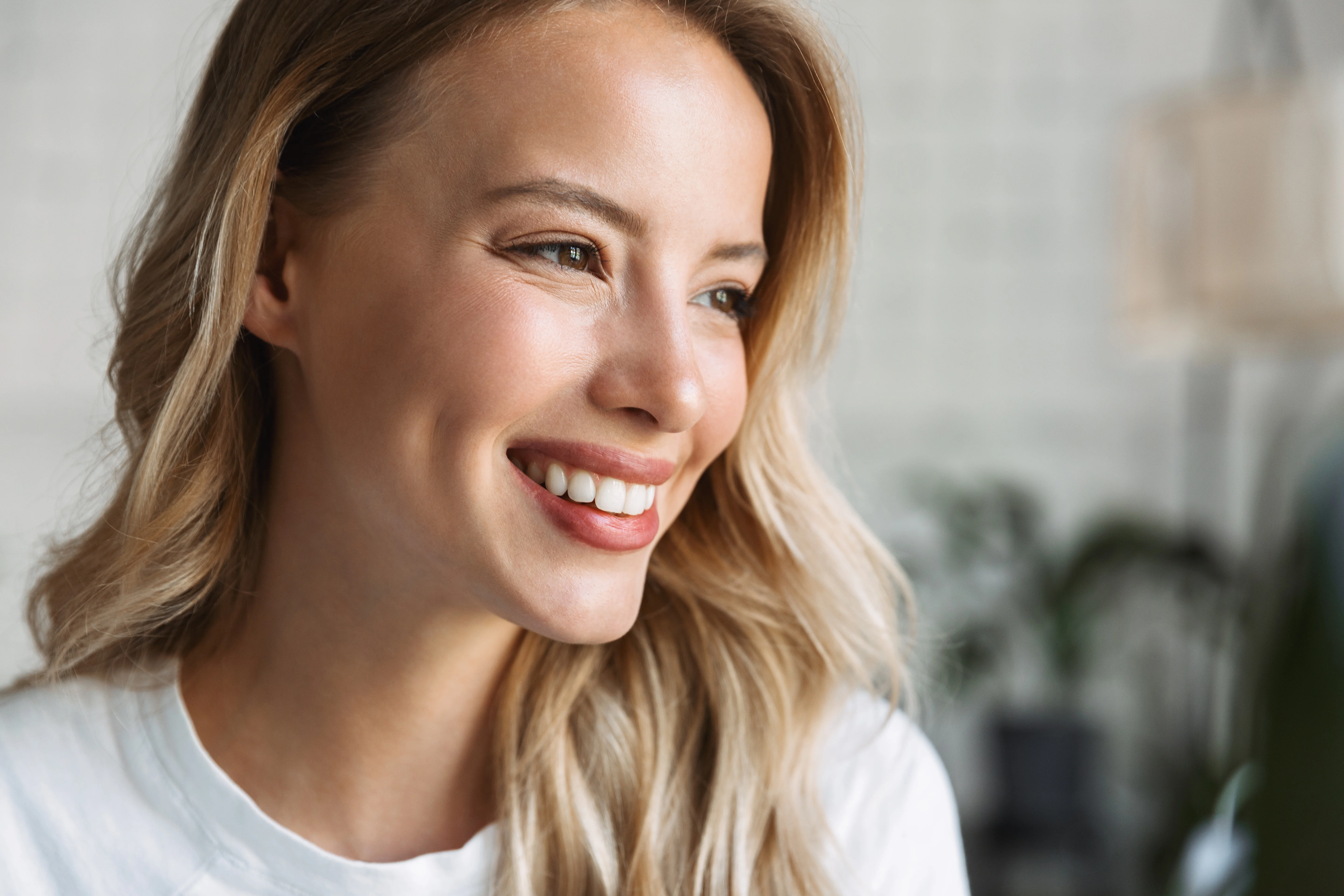 Side profile of a smiling woman with glowing, even-toned skin, illustrating subtle volume enhancement and refreshed contours after dermal filler treatment.