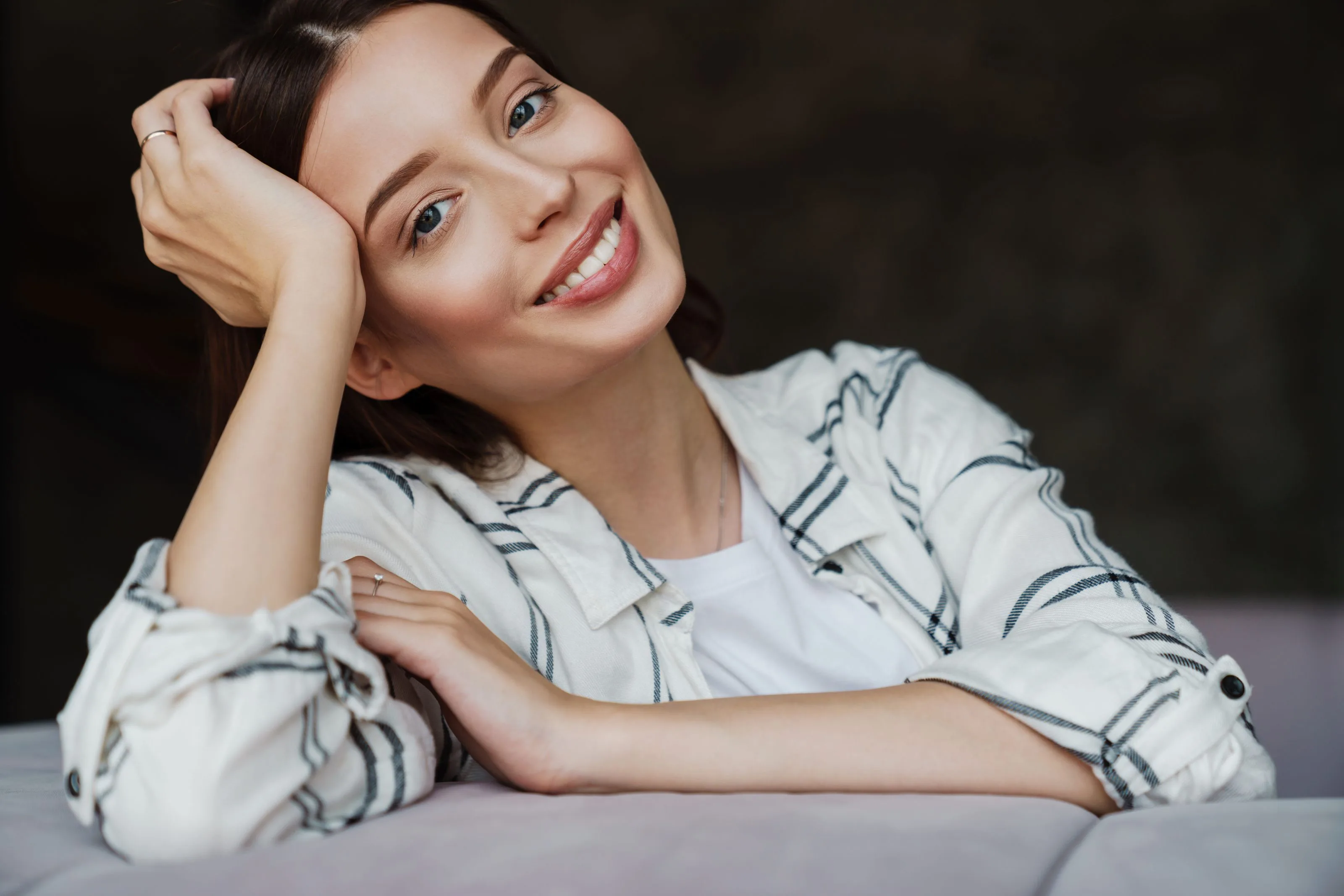 miling woman with clear, healthy skin wearing a casual striped shirt, representing the confidence that comes with a personalized skincare regimen.