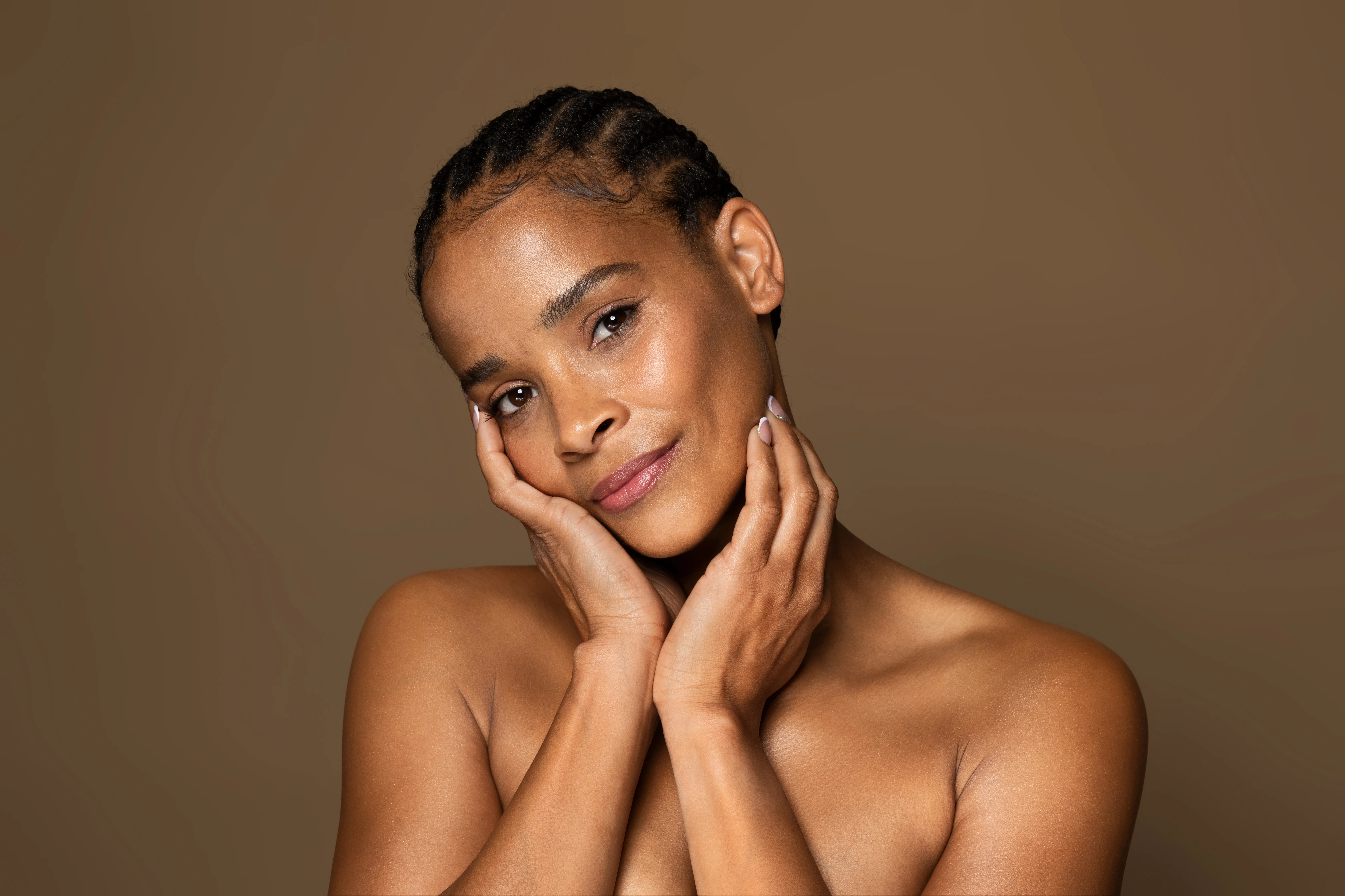 Confident woman with radiant skin gently holding her face after facelift and neck lift surgery