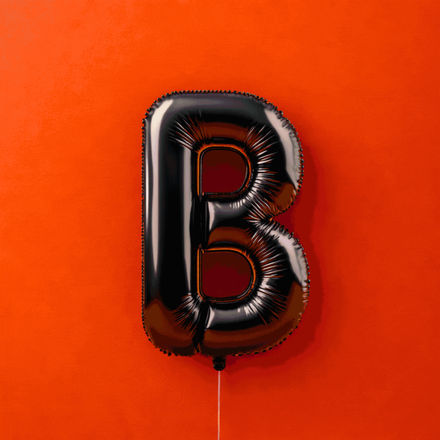 Palloncino nero a forma di lettera B su sfondo arancione.