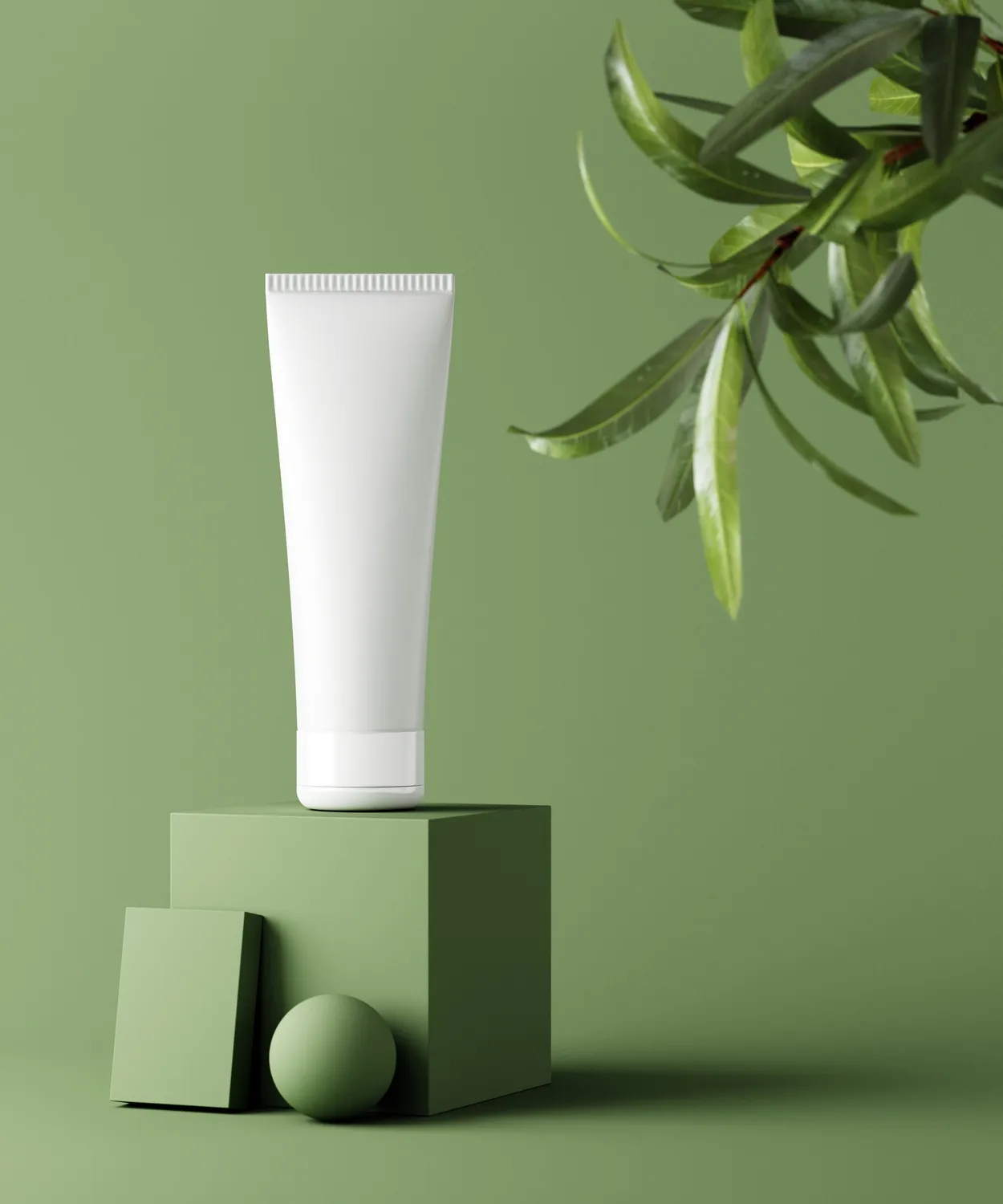 Tubo cosmetico bianco senza etichetta posizionato su un cubo verde con sfondo verde e rami di foglie verdi sul lato destro.