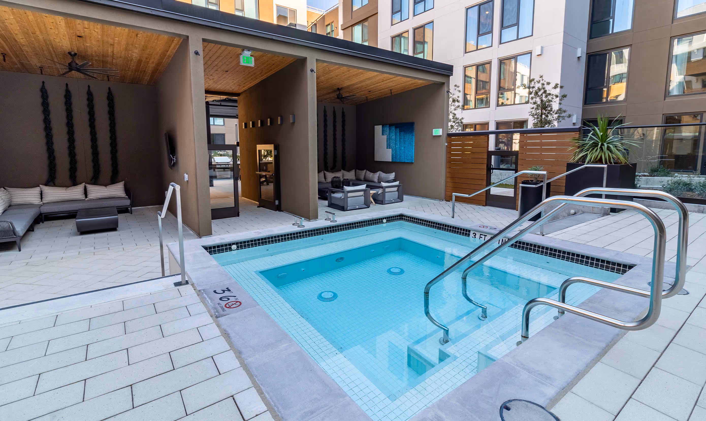 Modern residence courtyard with a small, inviting pool. Surrounding lounge chairs under a wooden pergola create a relaxed and upscale atmosphere.