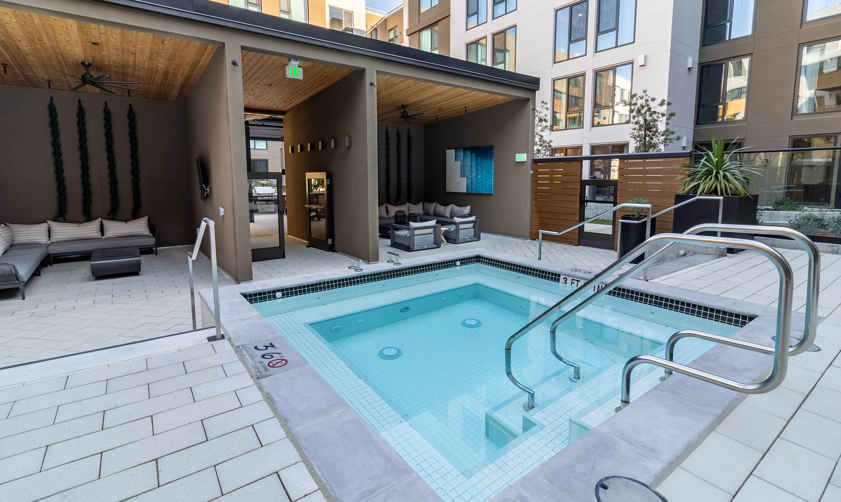Modern residence courtyard with a small, inviting pool. Surrounding lounge chairs under a wooden pergola create a relaxed and upscale atmosphere.
