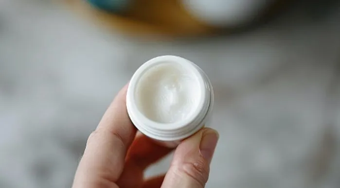 A view of a hand holding a small container of ointment, highlighting mupirocin uses for nose, rash, boils, and on an open wound.