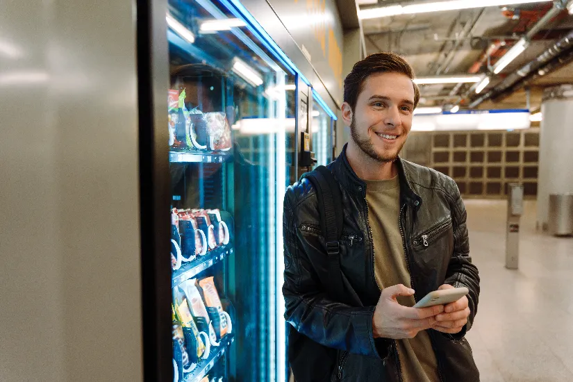 man next to vending machine smiling with phone