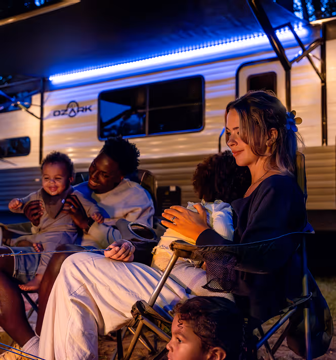 A family outside of their RV at night