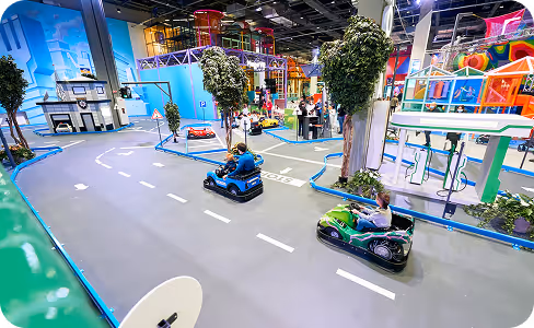 A group of people riding bumper cars down a street.