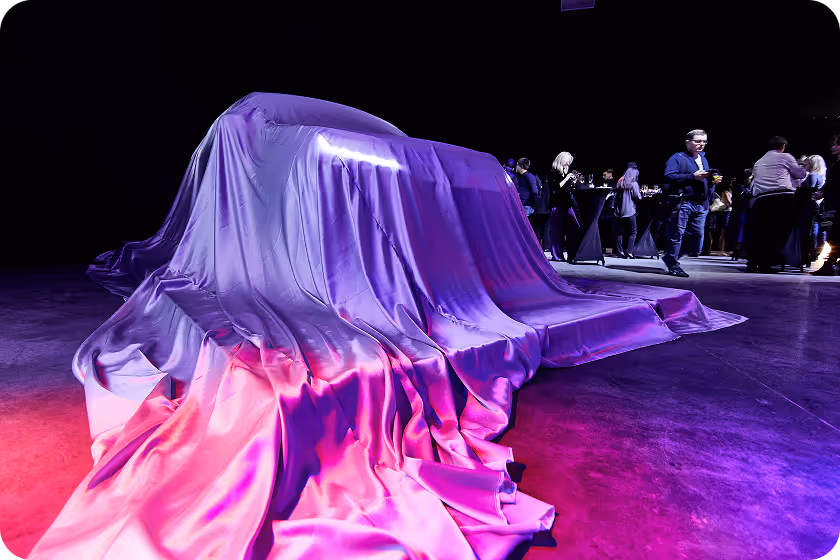 A car covered in a purple cloth on a stage.