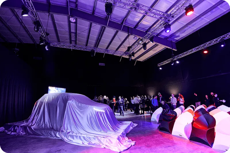 A group of people standing around a car covered in a sheet.