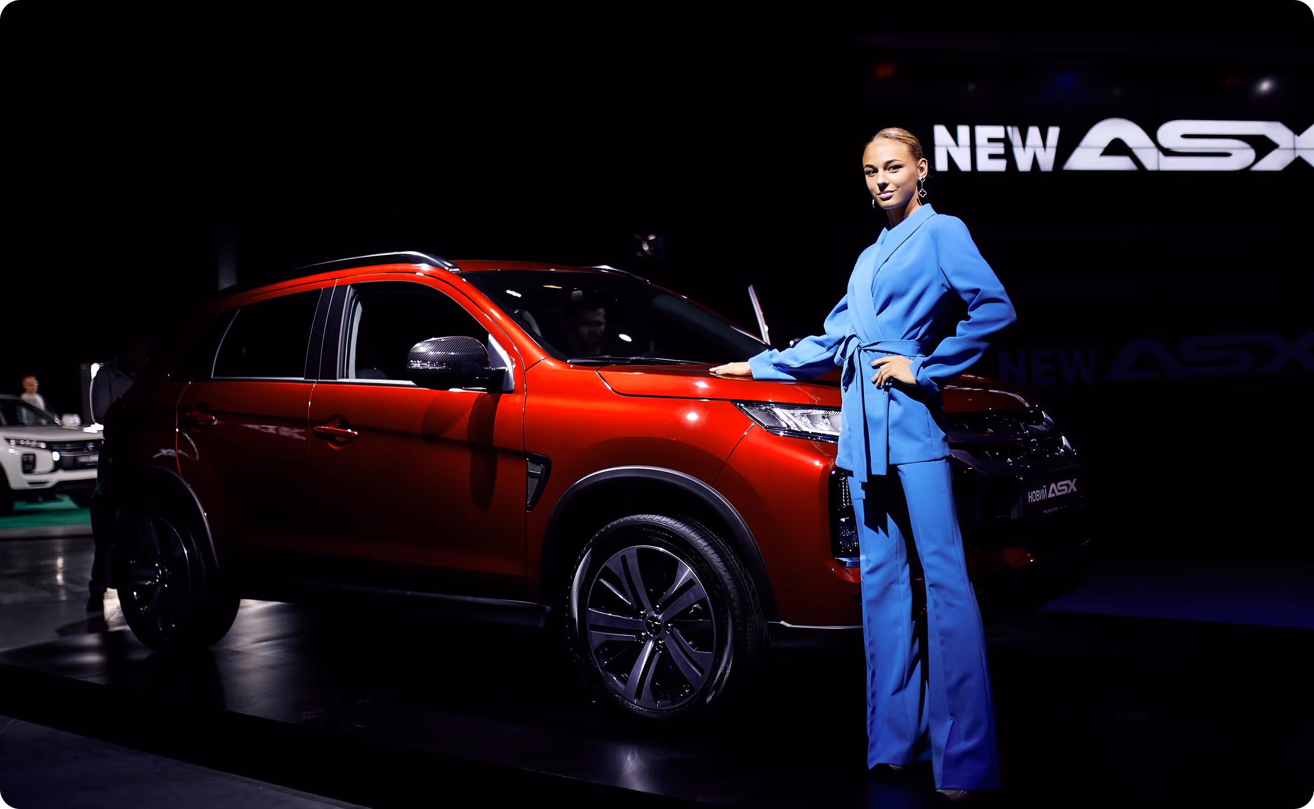 A woman standing next to a red suv.
