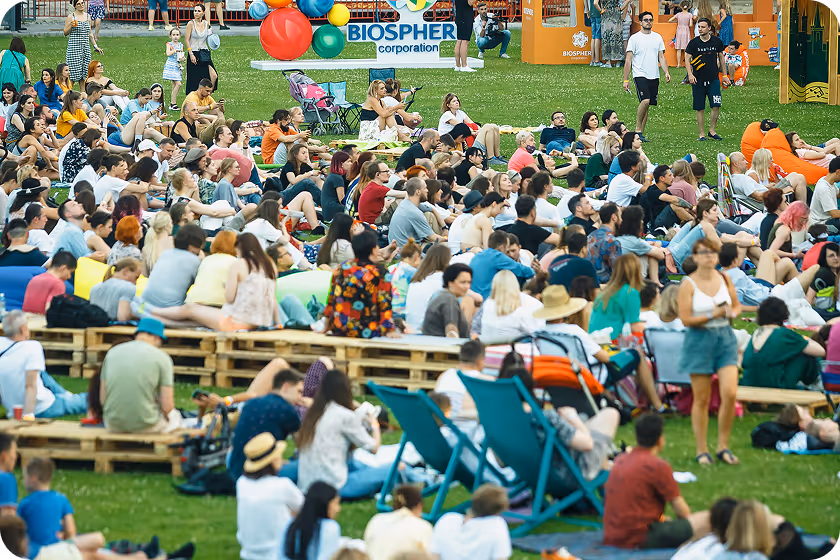 A crowd of people sitting on top of a lush green field.