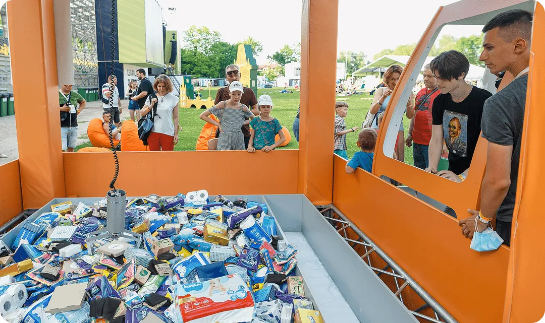 A group of people standing around a table covered in items.