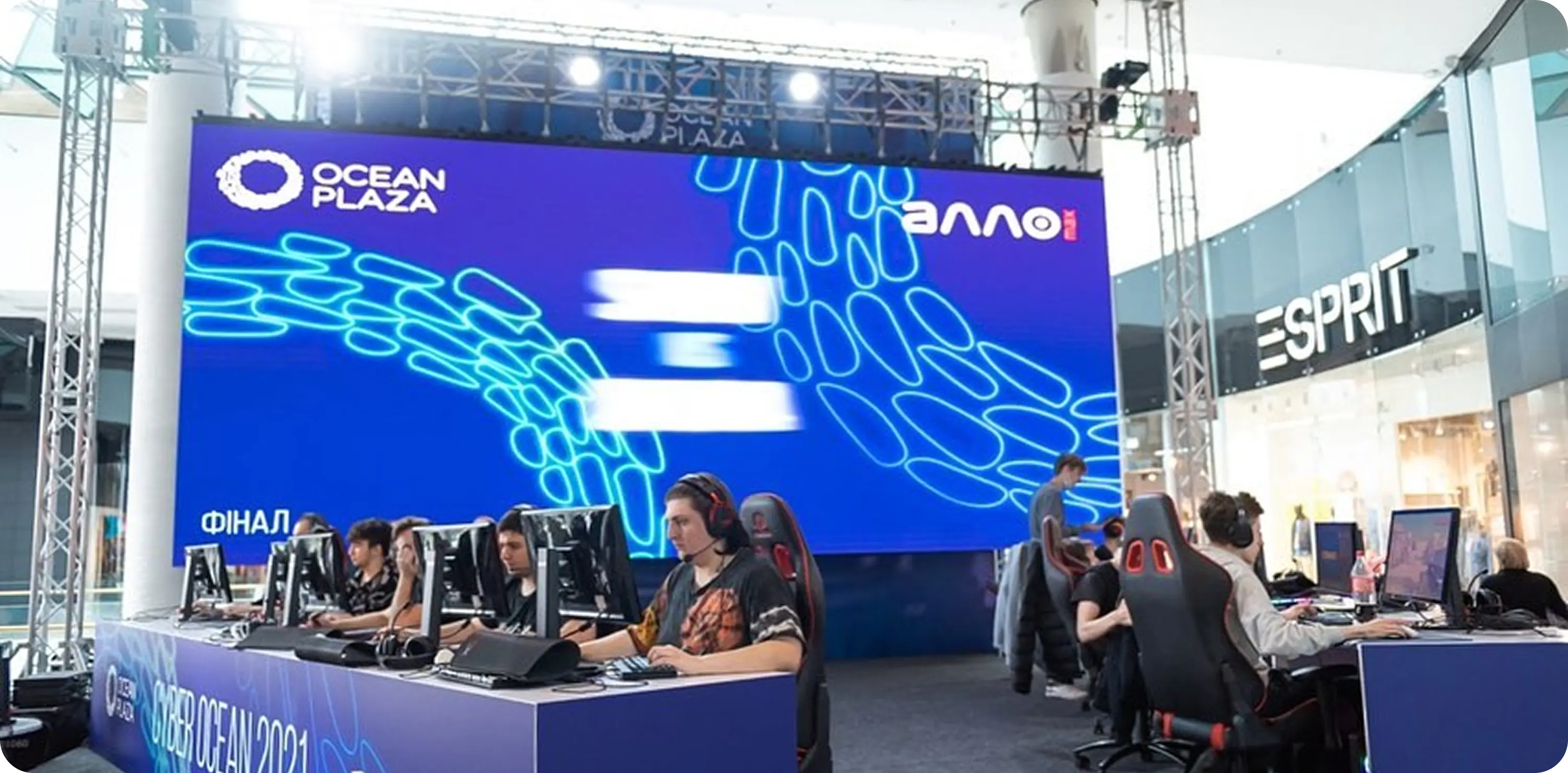 A group of people sitting at desks in front of a screen.