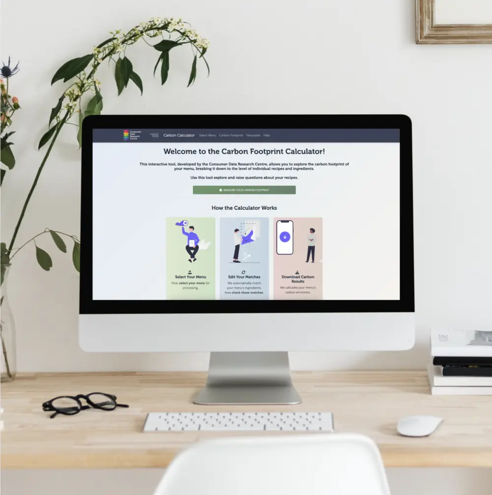 Laptop on desk displaying the Mapping Advertising Assets Project (MAAP) Leeds website, surrounded by a gold lamp, books, glasses, and a cup on a saucer.