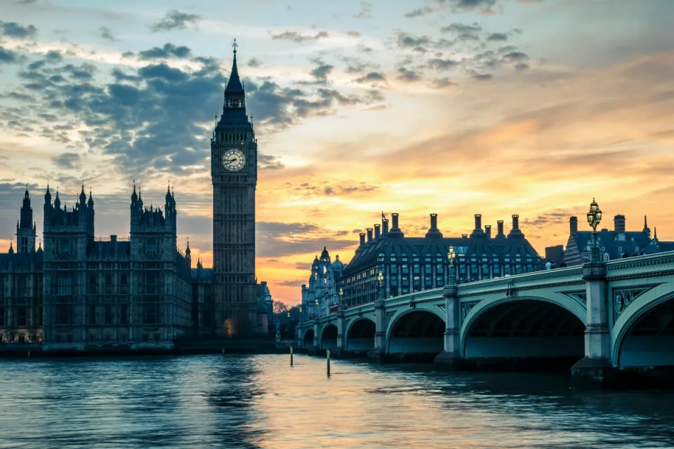 The Palace of Westminster and Big Ben silhouetted against a vibrant orange and blue sunset