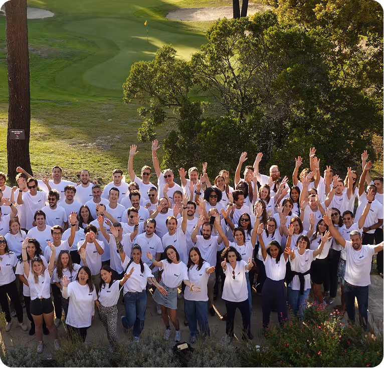 Groupe de personnes portant des t-shirts blancs Neat, souriantes et levant les mains en l'air dans un environnement extérieur verdoyant.