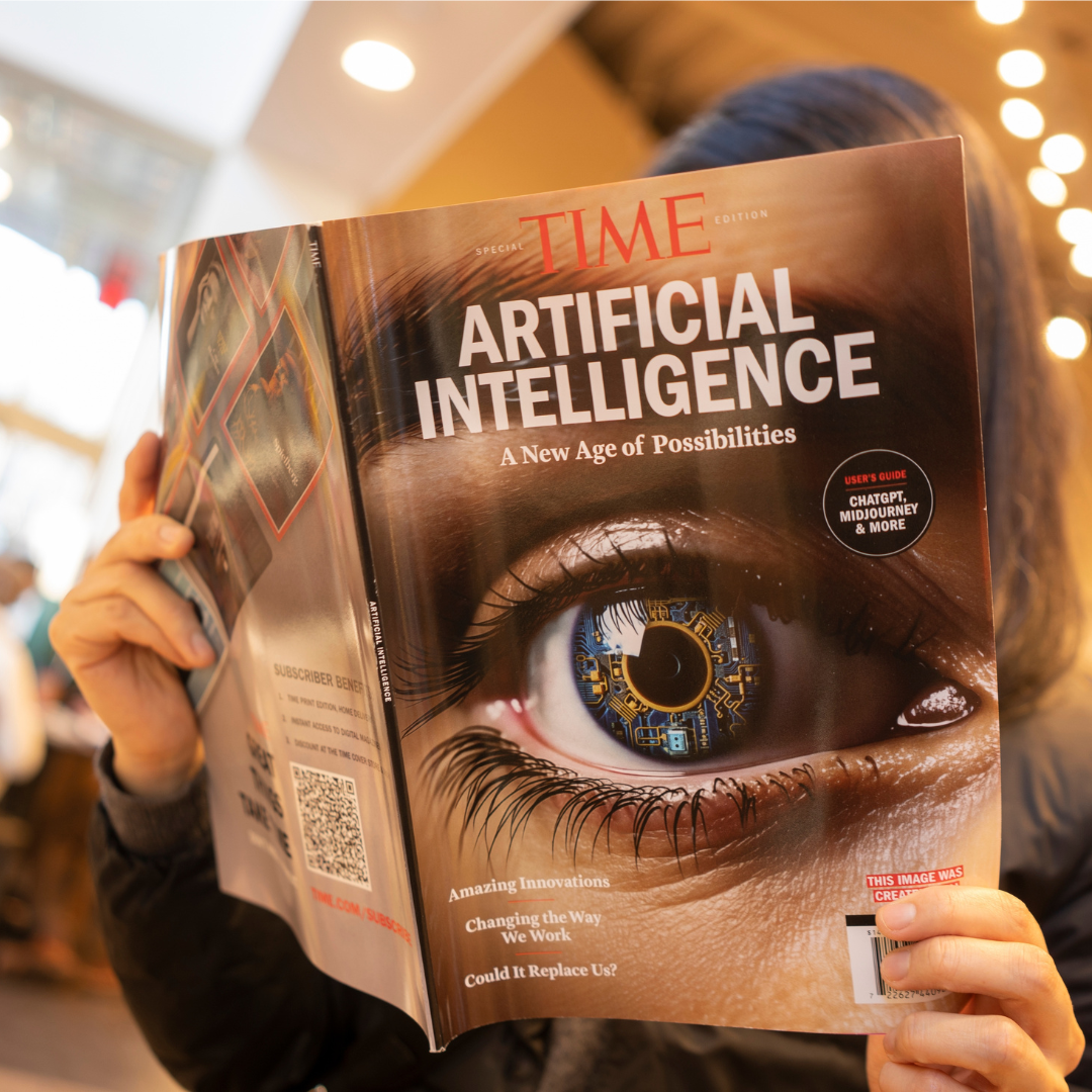 Person holding and reading a TIME magazine issue featuring “Artificial Intelligence” with a close-up eye and digital circuit design on the cover.