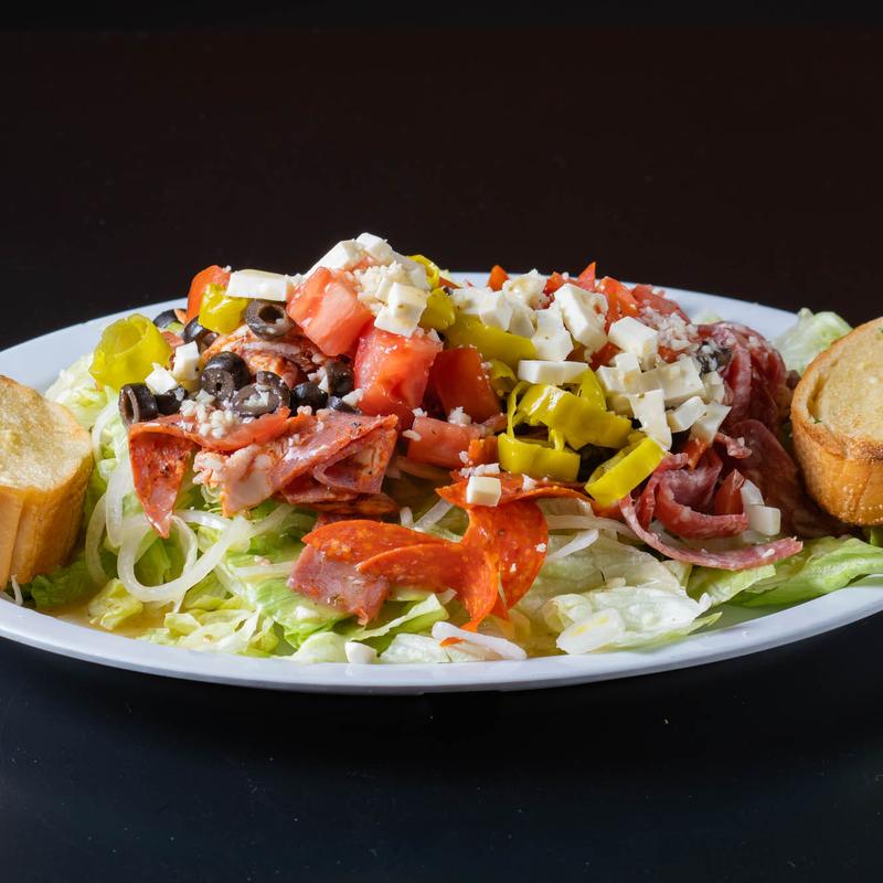 Salad topped with various meats, with a side of bread