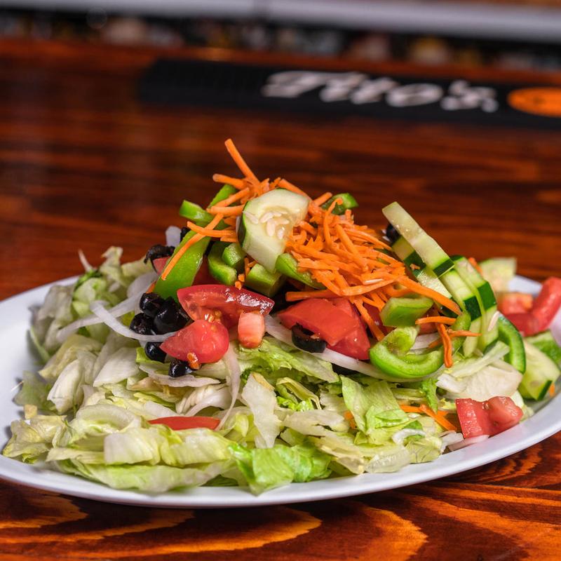 A salad platter with various vegetables on top of a wooden table.