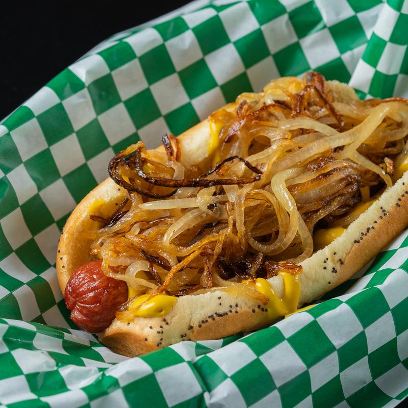 Hot dog topped with caramelized onions on top of a tray