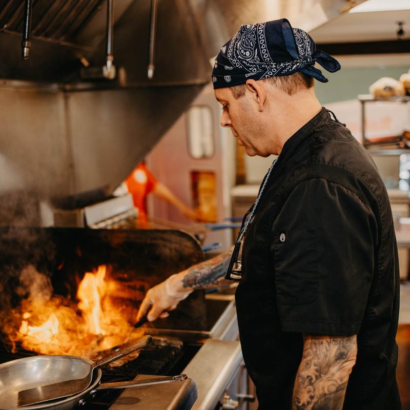 Chef in front of a grill, cooking with high flames