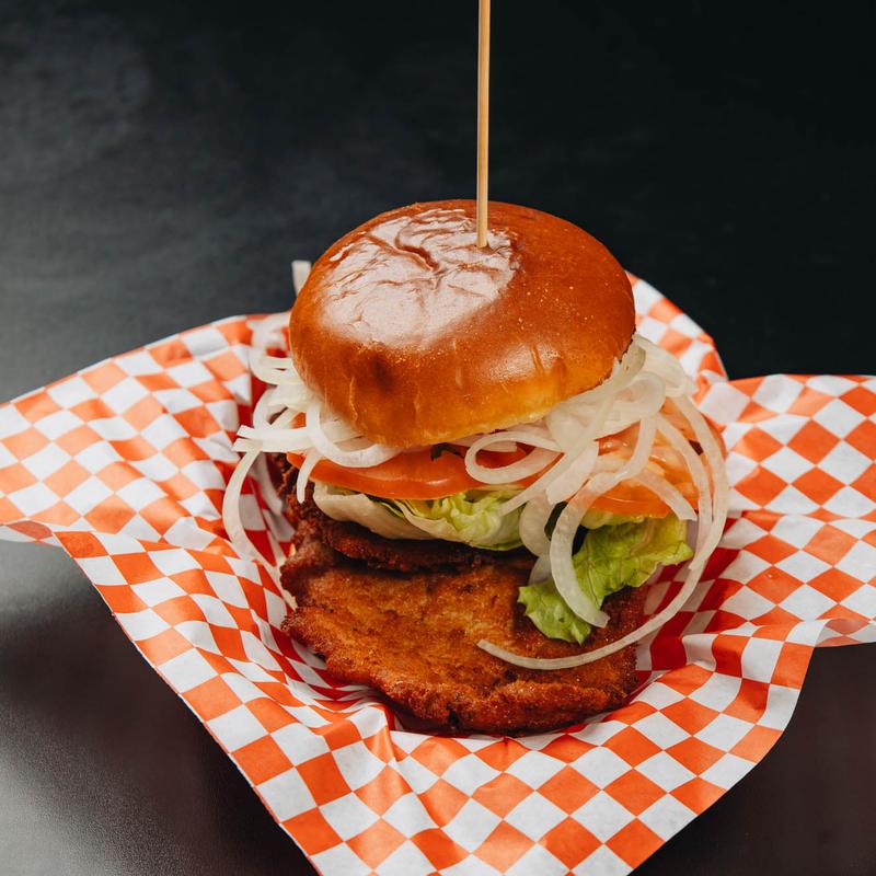 Hamburger with a wooden stick on top of a tray.