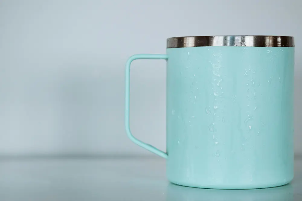 Close-up of a turquoise reusable cup with condensation.