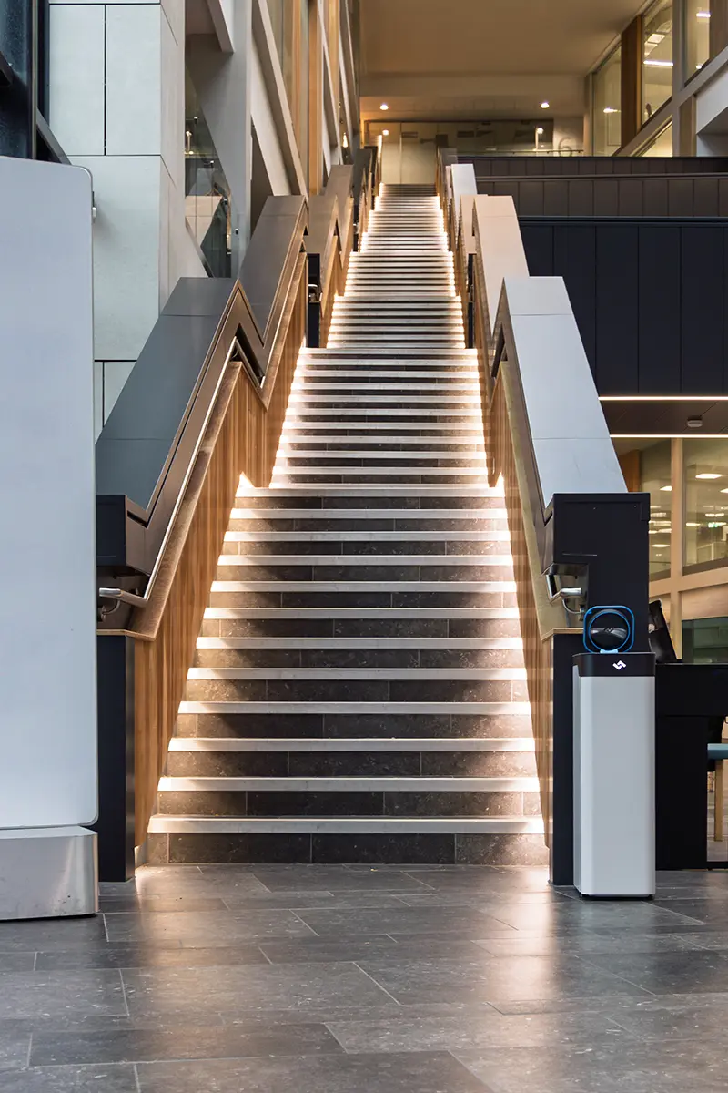Wide illuminated staircase in a modern building with an instarinse cup cleaning machine promoting reusables.