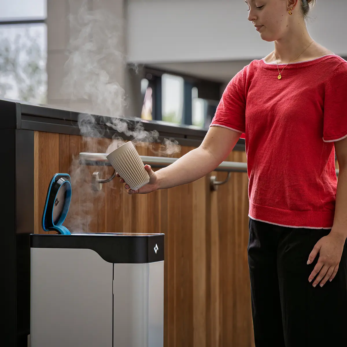 Woman using instarinse cup cleaning machine for safe sustainable cup reuse.