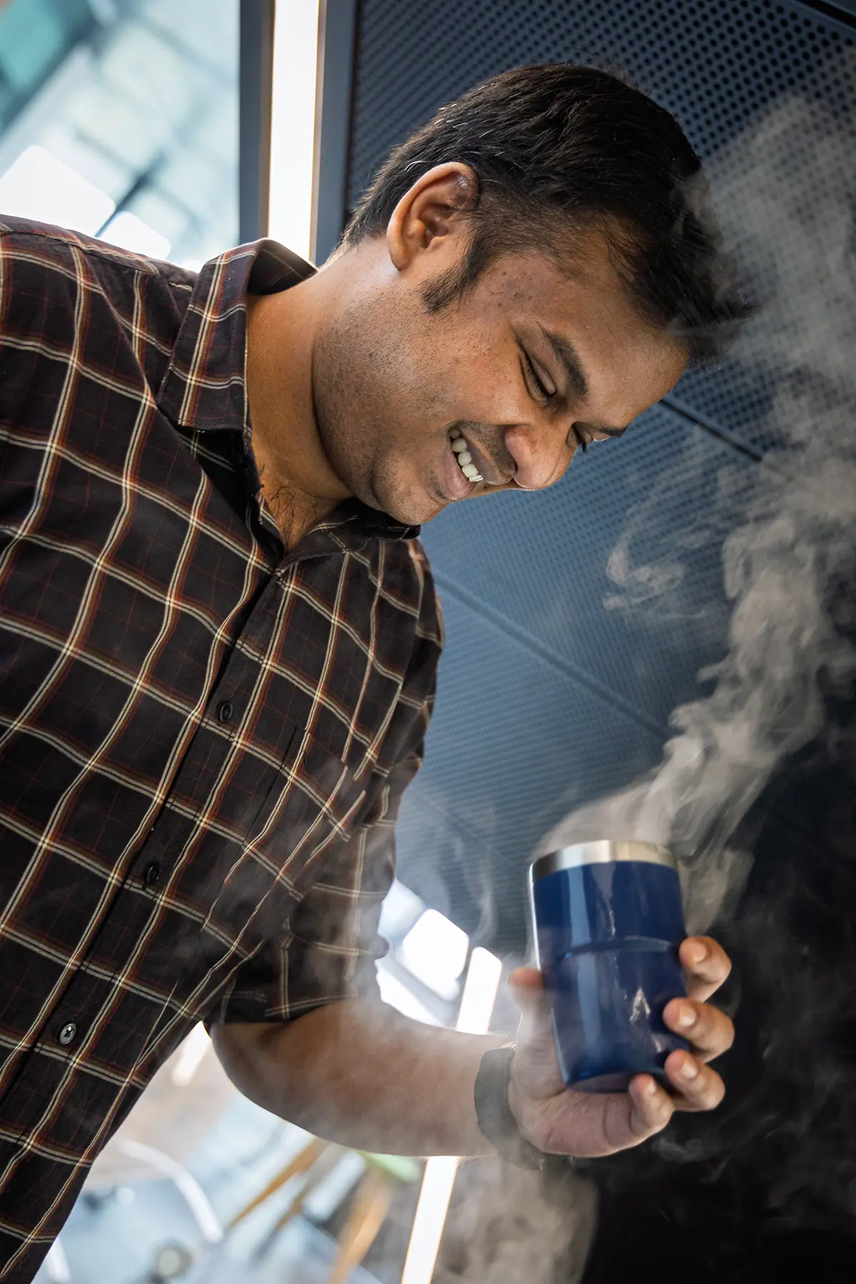 Person smiling while using instarinse cup cleaning machine to support reusable coffee cups and sustainability.