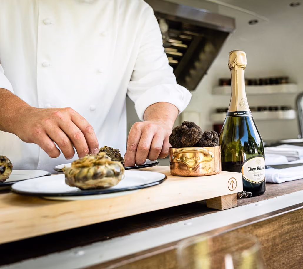 Chef Yann Nury placing food on a plate inside the airstream kitchen