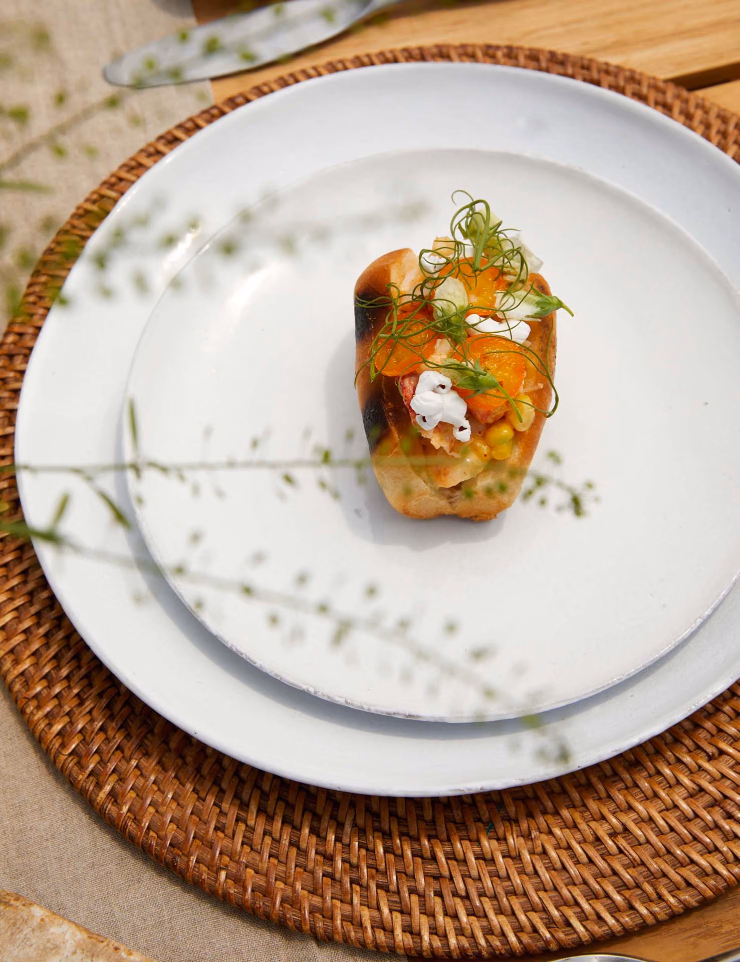 Small toast topped with seafood salad, corn, and fennel on a woven placemat