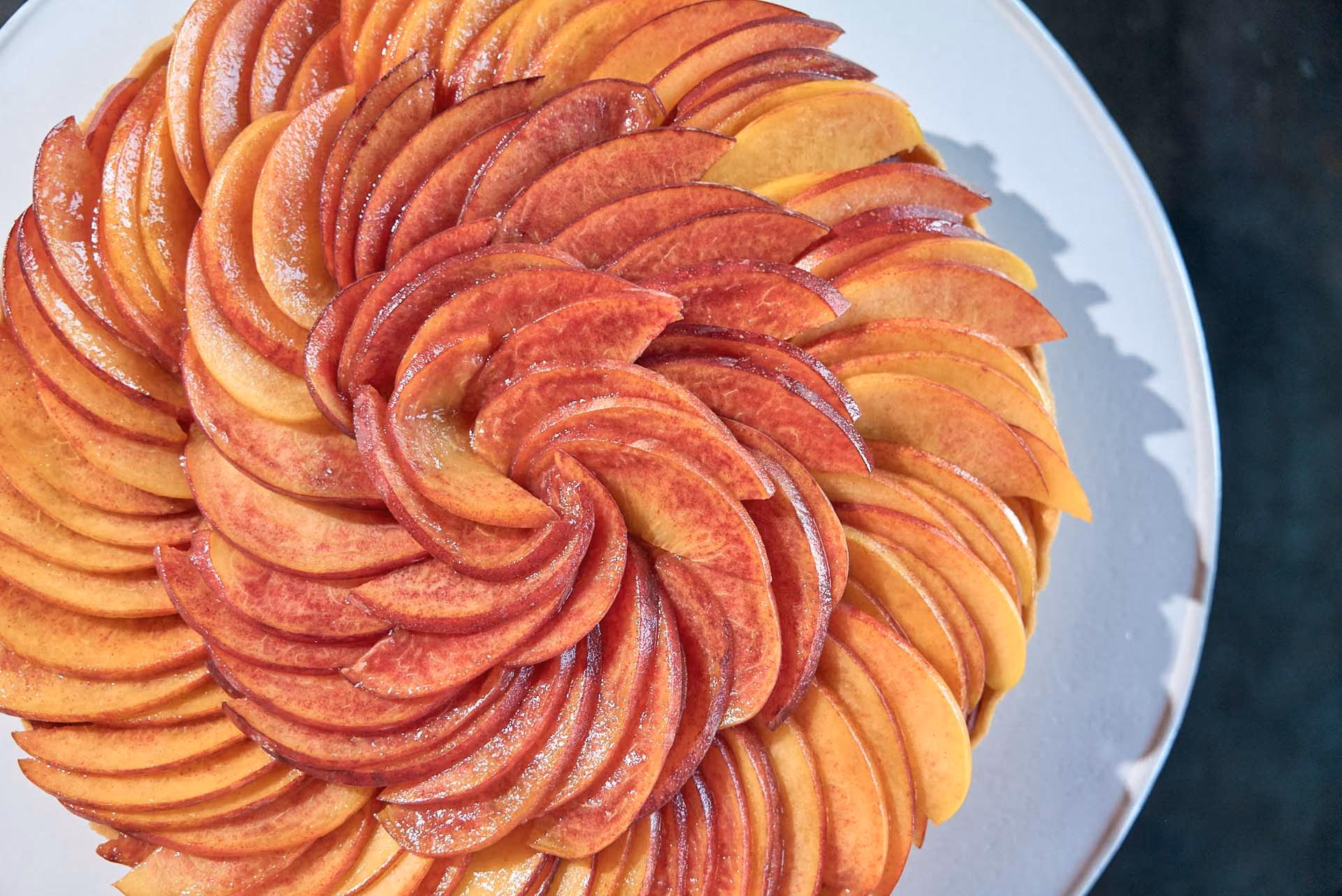 Overhead close-up of a tart topped with a spiral of sliced peaches