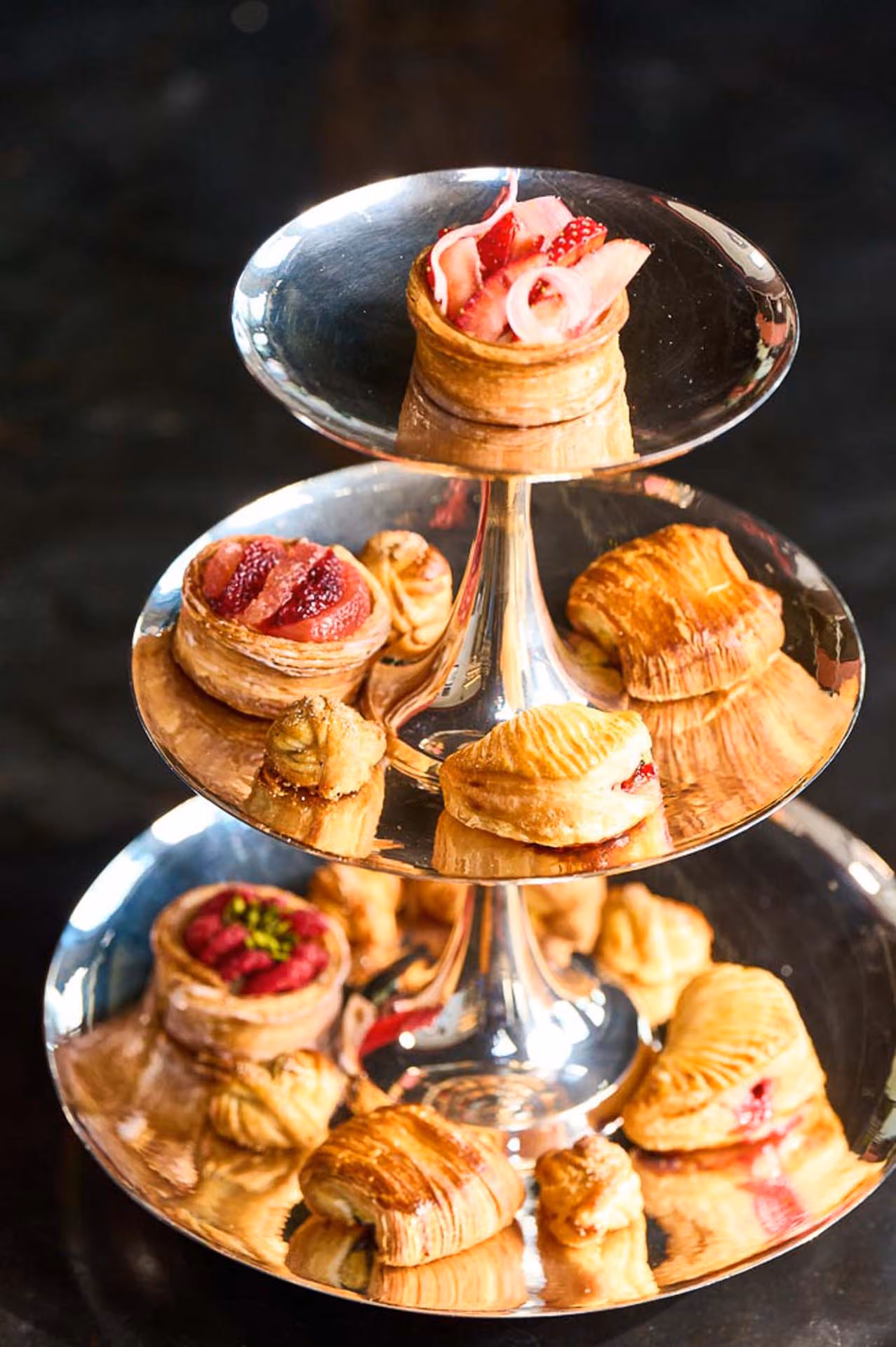 Three-tiered silver stand of pastries topped with fruit