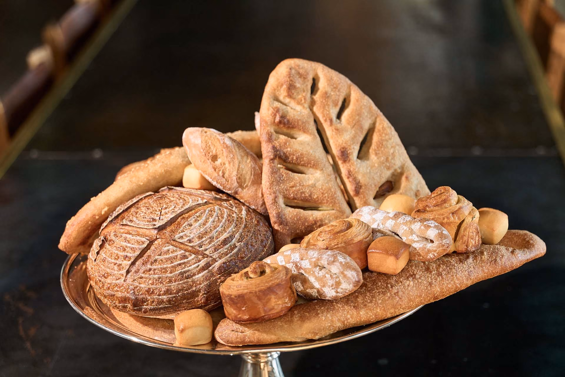 Assorted fresh-baked breads and pastries piled on a silver stand