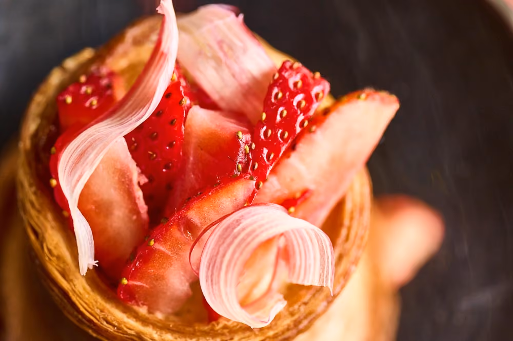 Overhead close-up of a pastry cup filled with strawberries and rhubarb ribbons