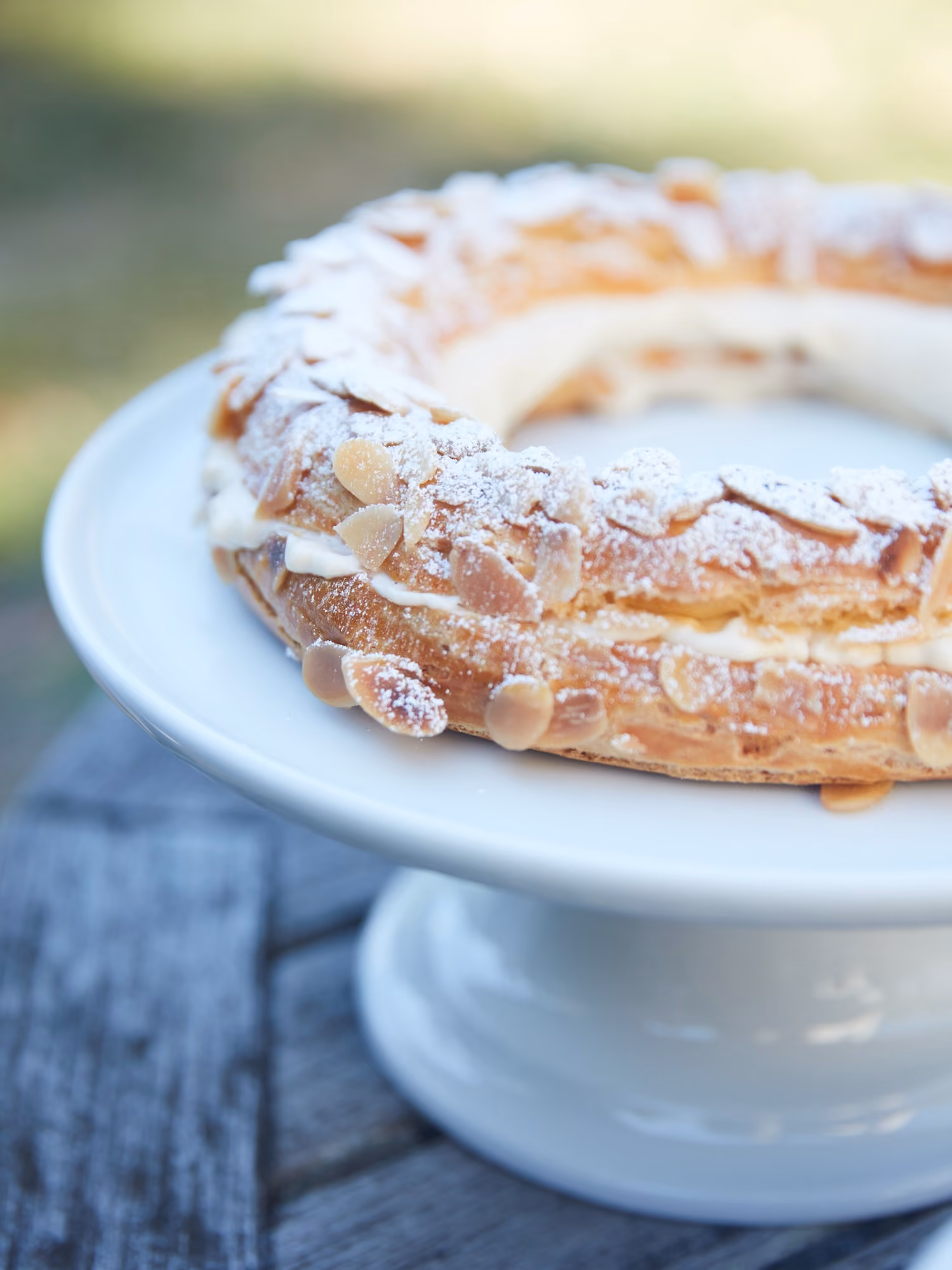 Close-up of a Paris-Brest pastry ring topped with almonds and powdered sugar