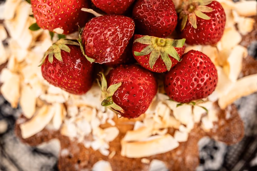 Overhead close-up of fresh strawberries and toasted coconut on a tart