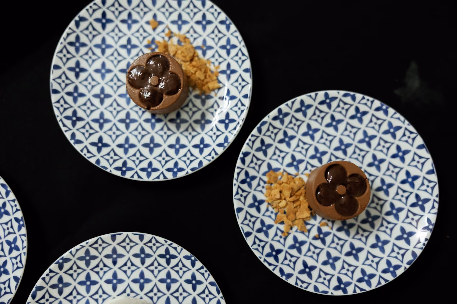 Overhead view of flower-shaped chocolate desserts topped with crumble on patterned plates