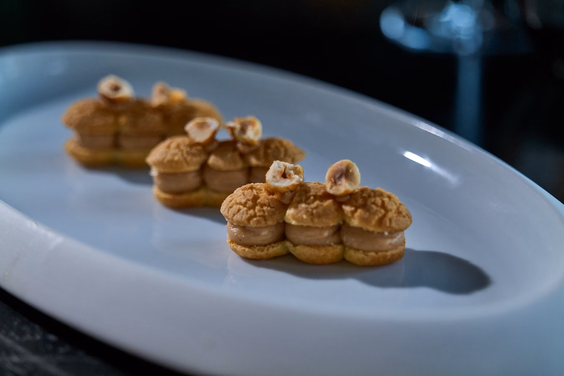 Three eclair-shaped pastries topped with hazelnuts