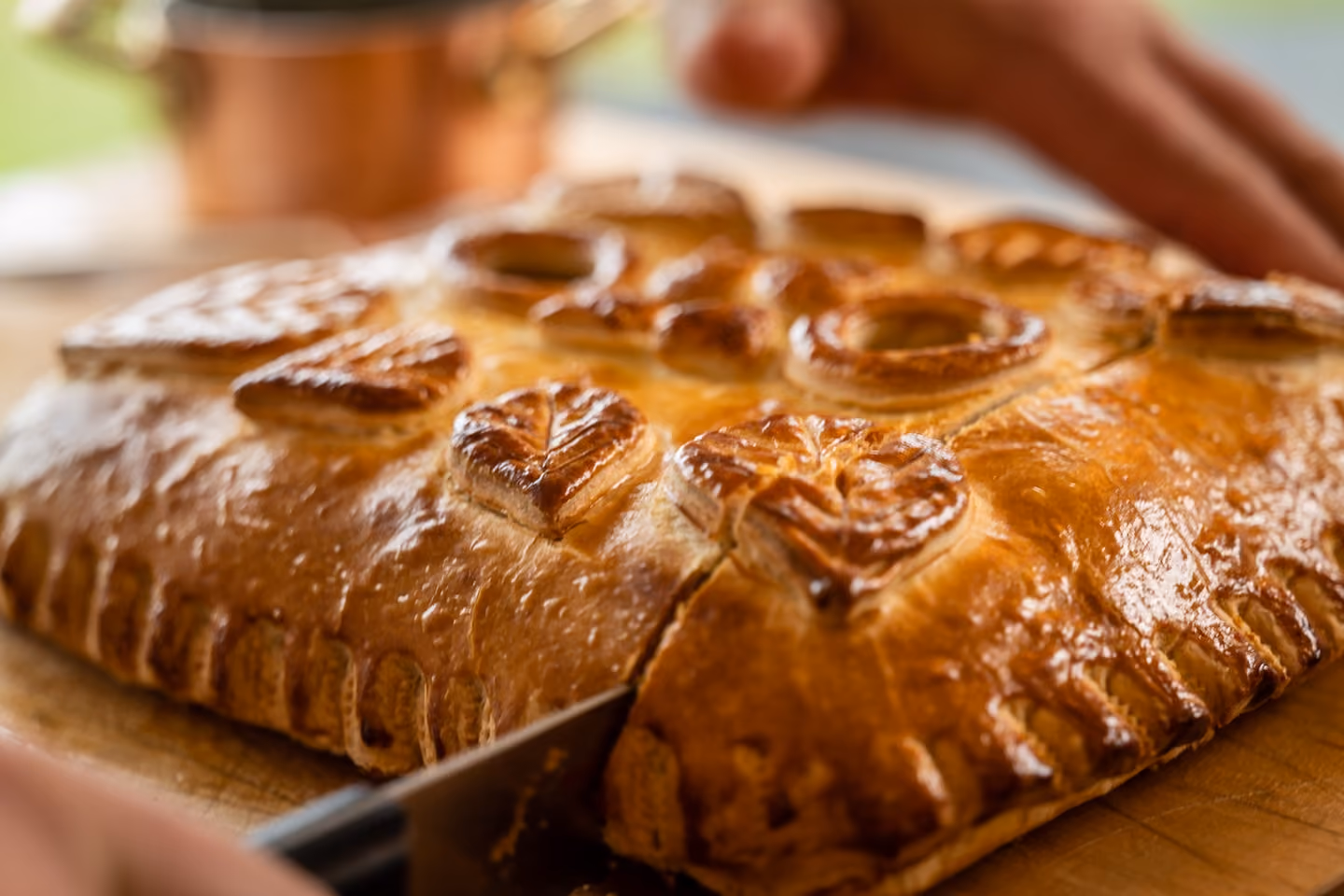 Golden beef Wellington pastry with decorative pastry leaves being sliced