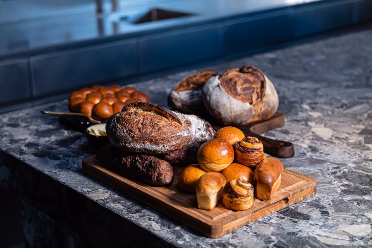Assortment of fresh baked breads and rolls arranged on a wooden board