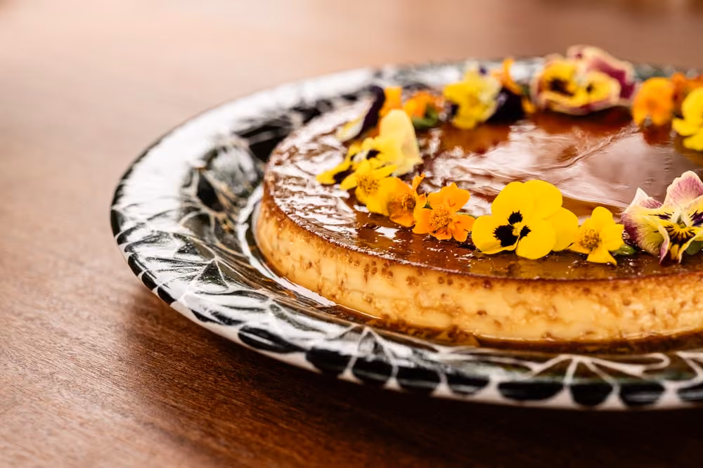 Whole caramel flan garnished with a ring of edible flowers