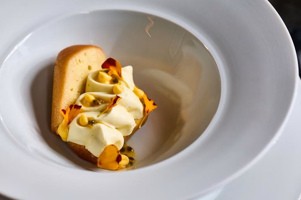Pound cake topped with whipped mousse, passion fruit, and orange flowers