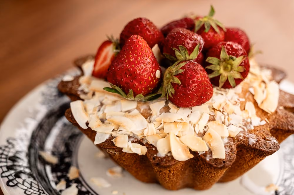 Tart topped with fresh strawberries and toasted coconut flakes